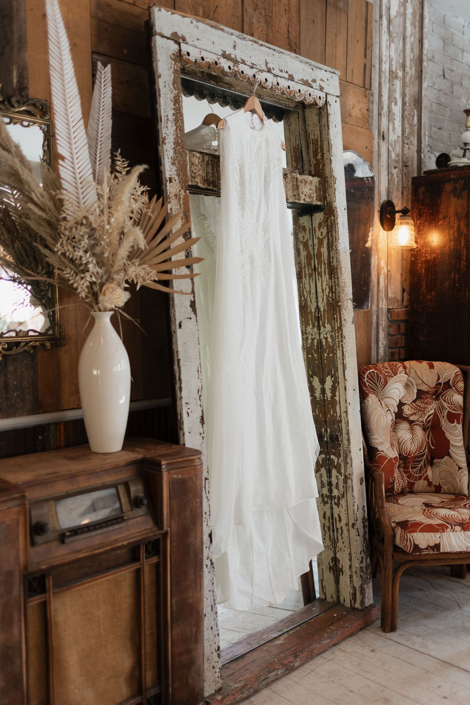 Rustic wedding venue interior with white curtains and dried floral arrangements.