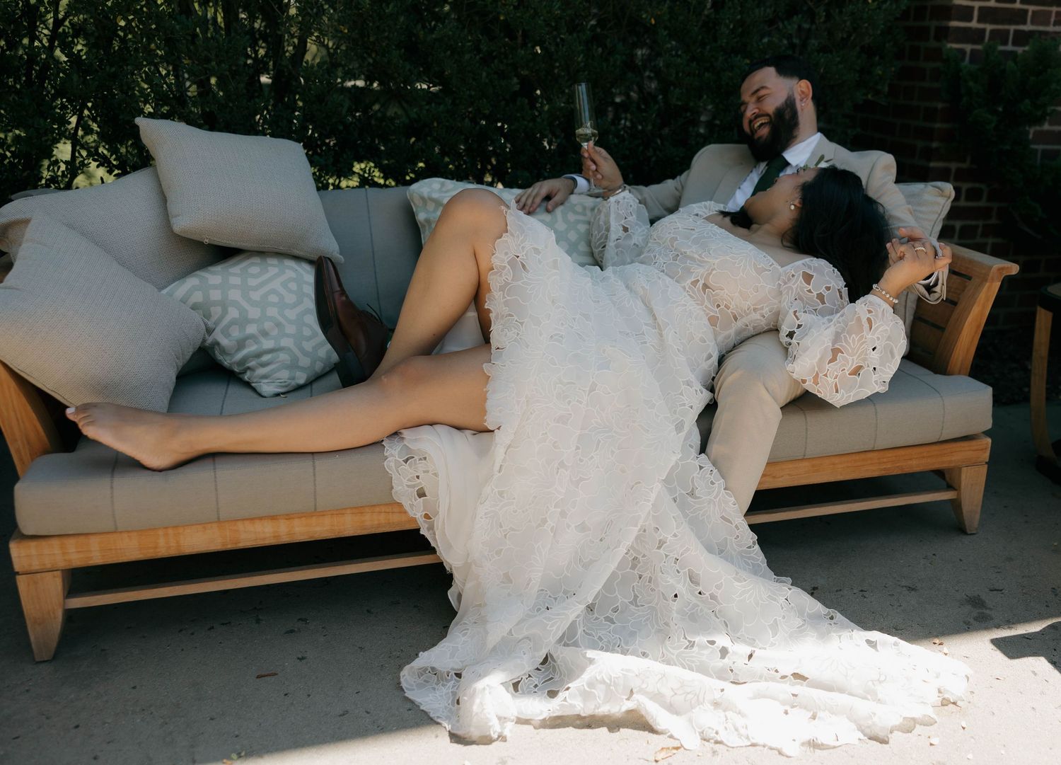 Couple relaxing on outdoor lounge furniture at wedding reception.