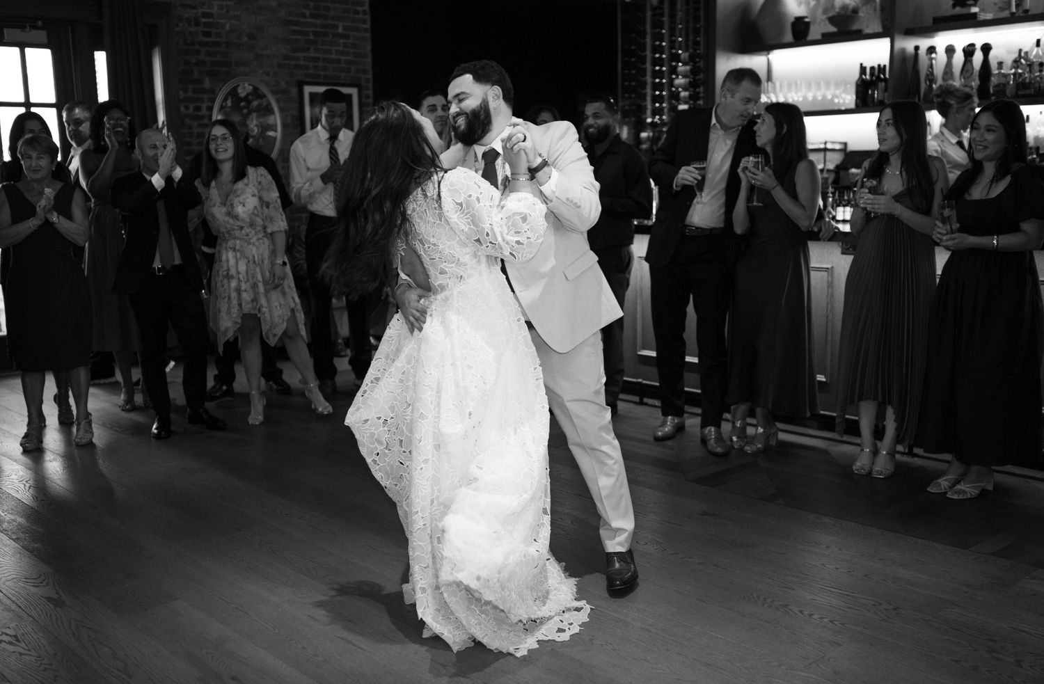 A couple shares their first dance at their wedding reception in a rustic brick-walled venue.