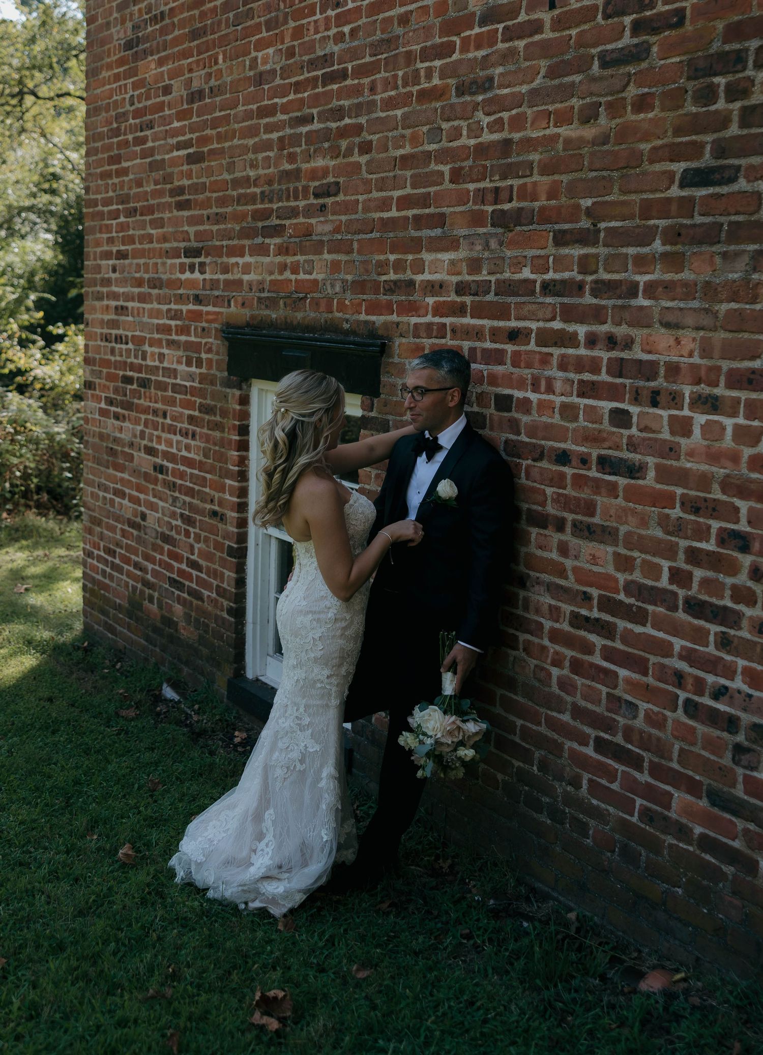 A romantic moment shared against a rustic brick wall during a wedding photoshoot.
