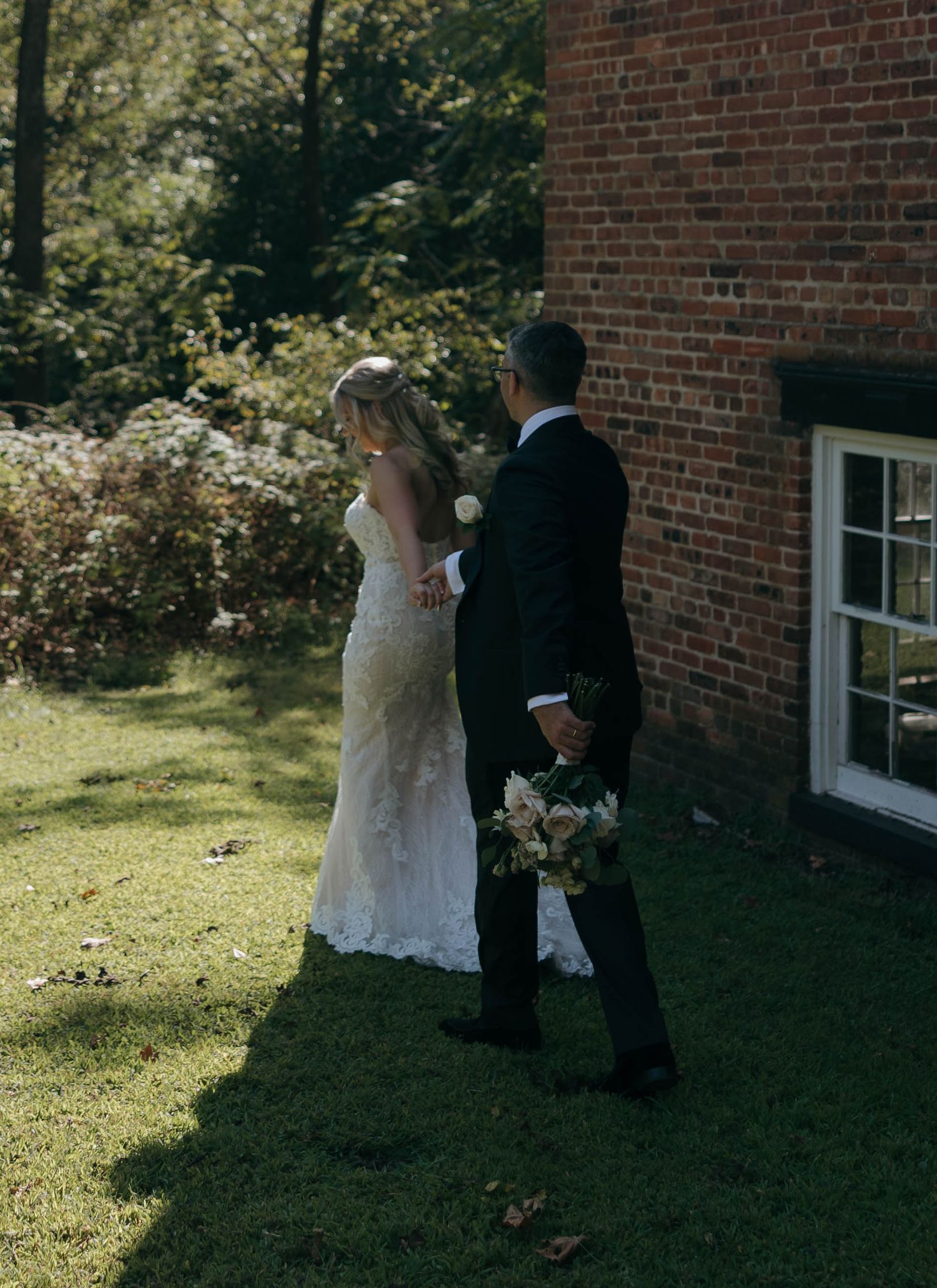 A couple shares a tender first look moment outside a brick building on their wedding day.