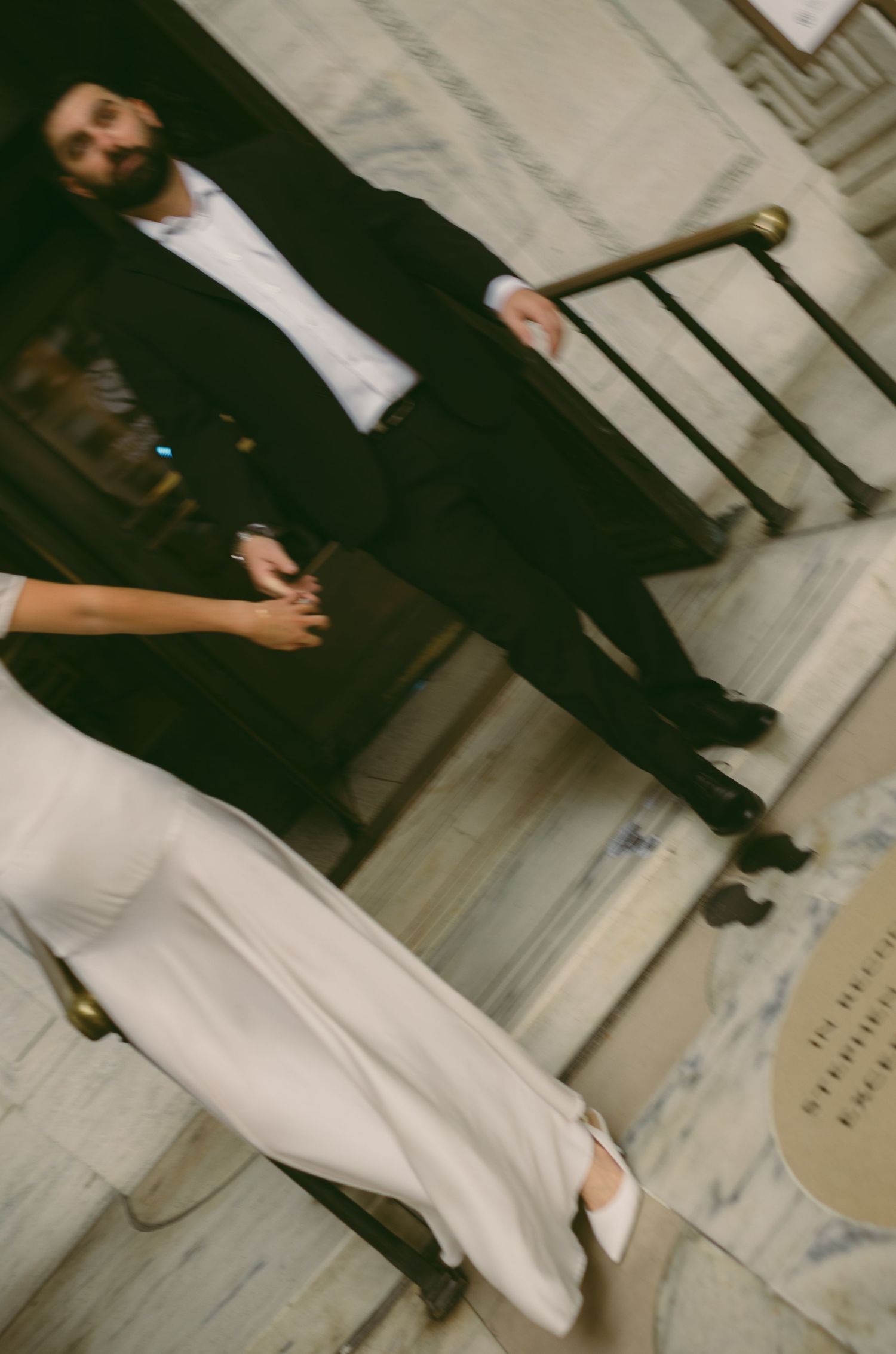 A couple in formal attire walking together in a stylish urban setting.