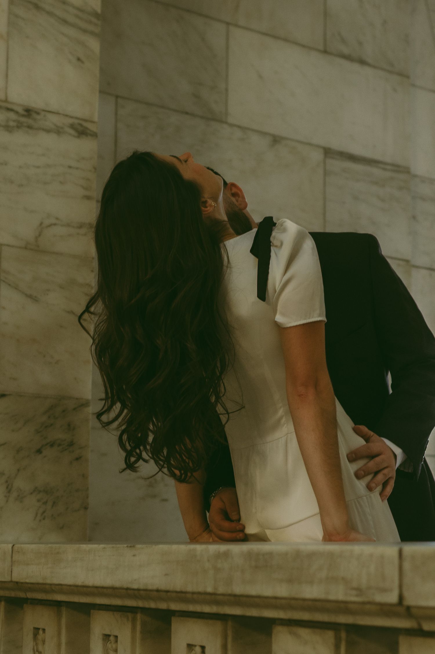 A romantic moment captured against marble architecture and decorative stonework.