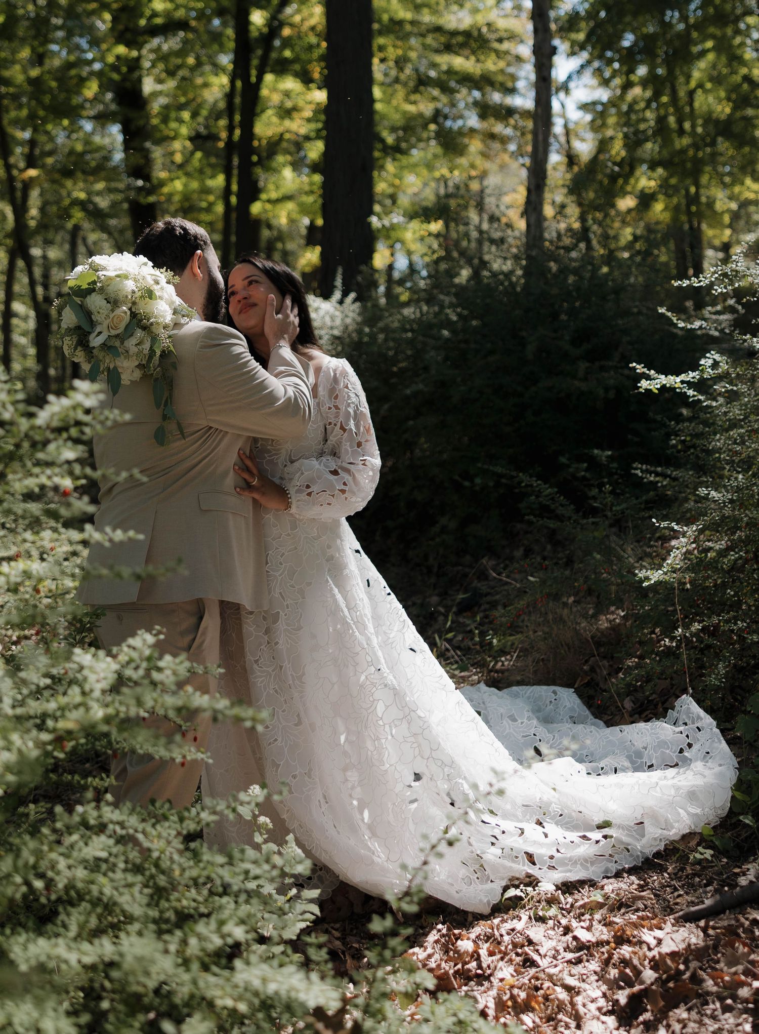 A wedding couple twirls through fallen leaves in a serene forest setting.