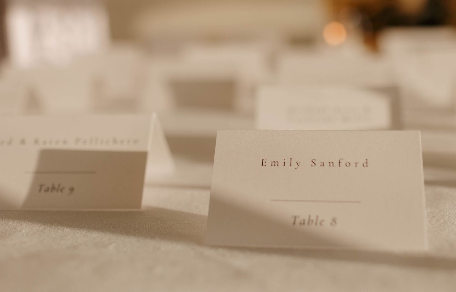 Close-up of elegant place cards on a white tablecloth.
