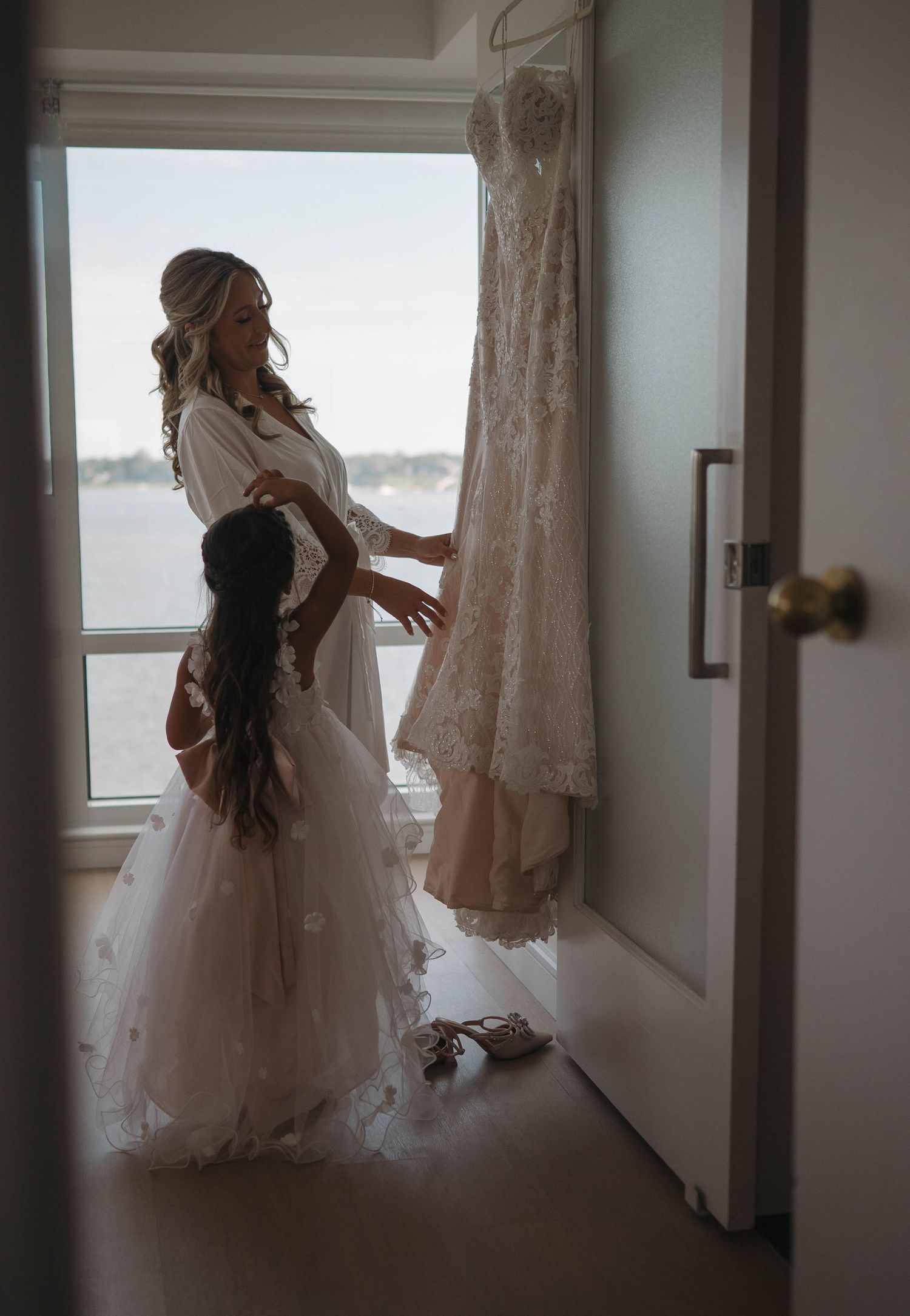 A flowing white wedding dress hanging by a window with natural light.