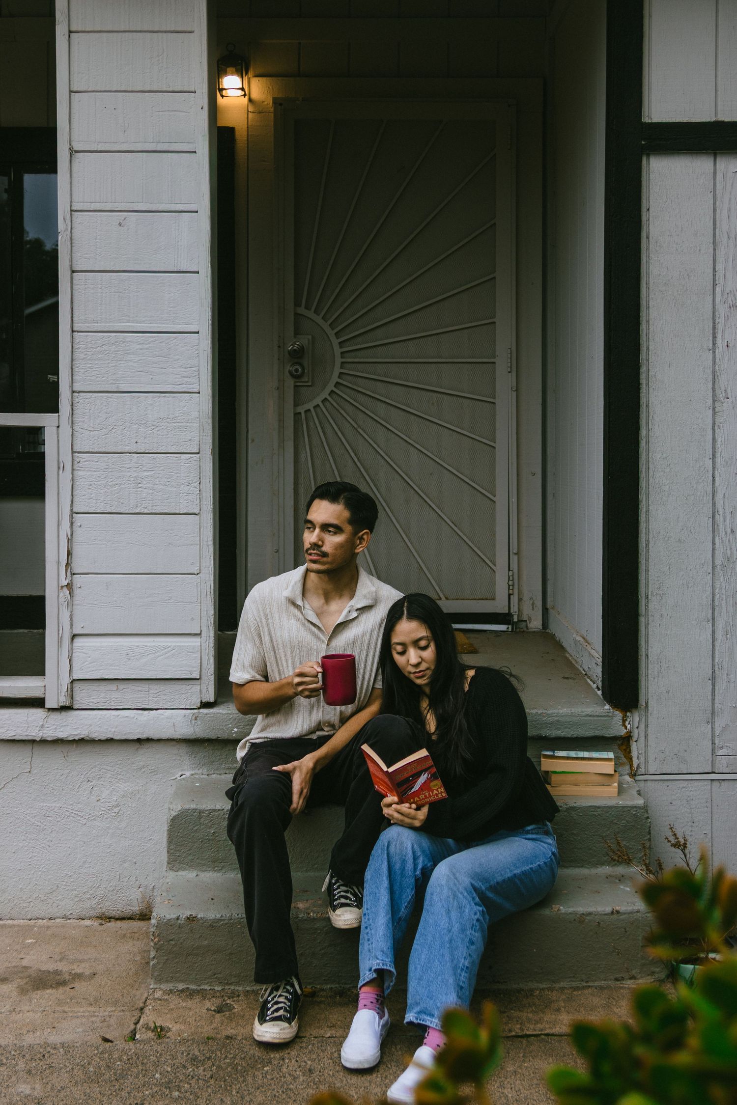 Couple sitting on front porch steps sharing a quiet moment with books.