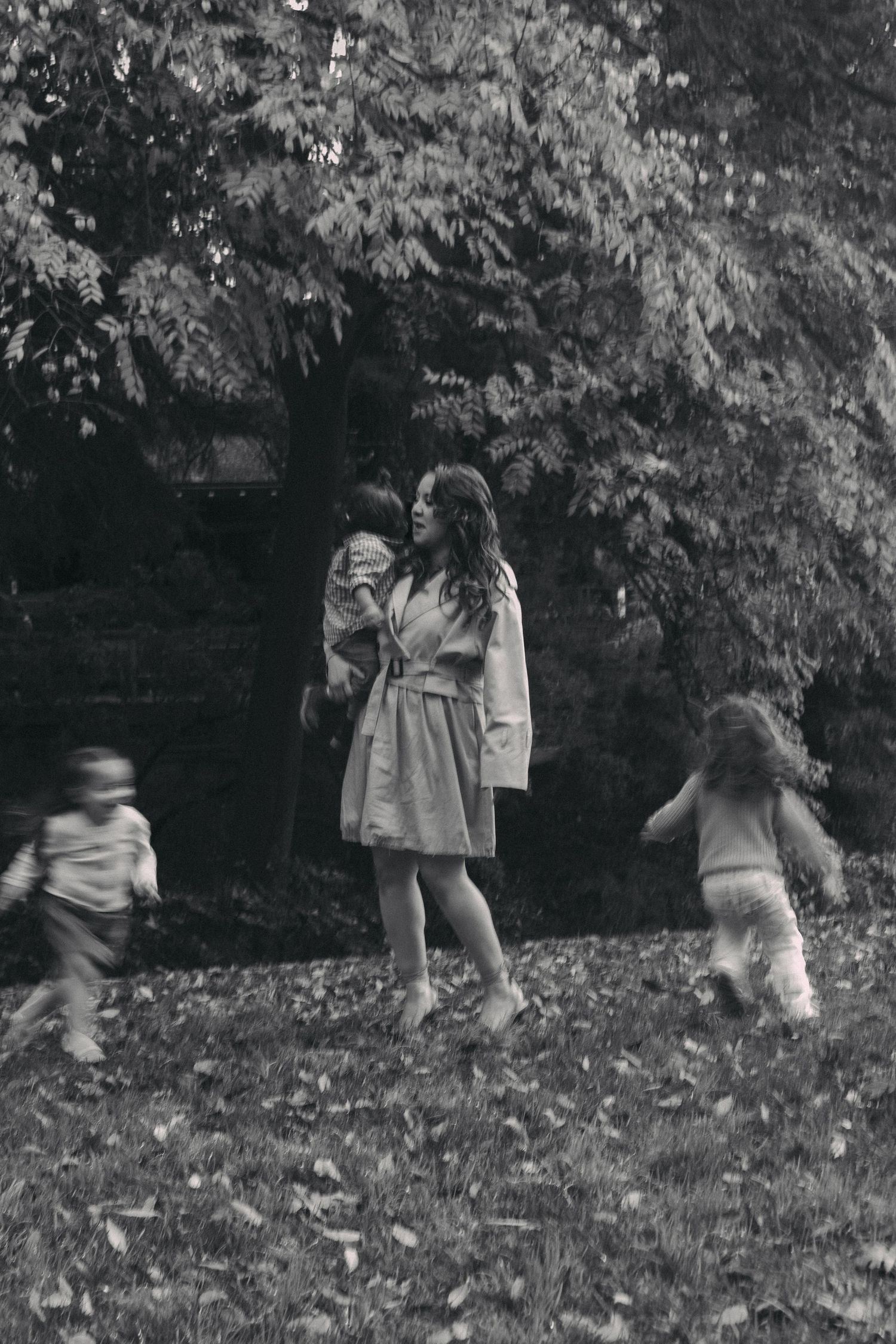 A sequence of black and white photos showing children playing and jumping in fallen autumn leaves outdoors.