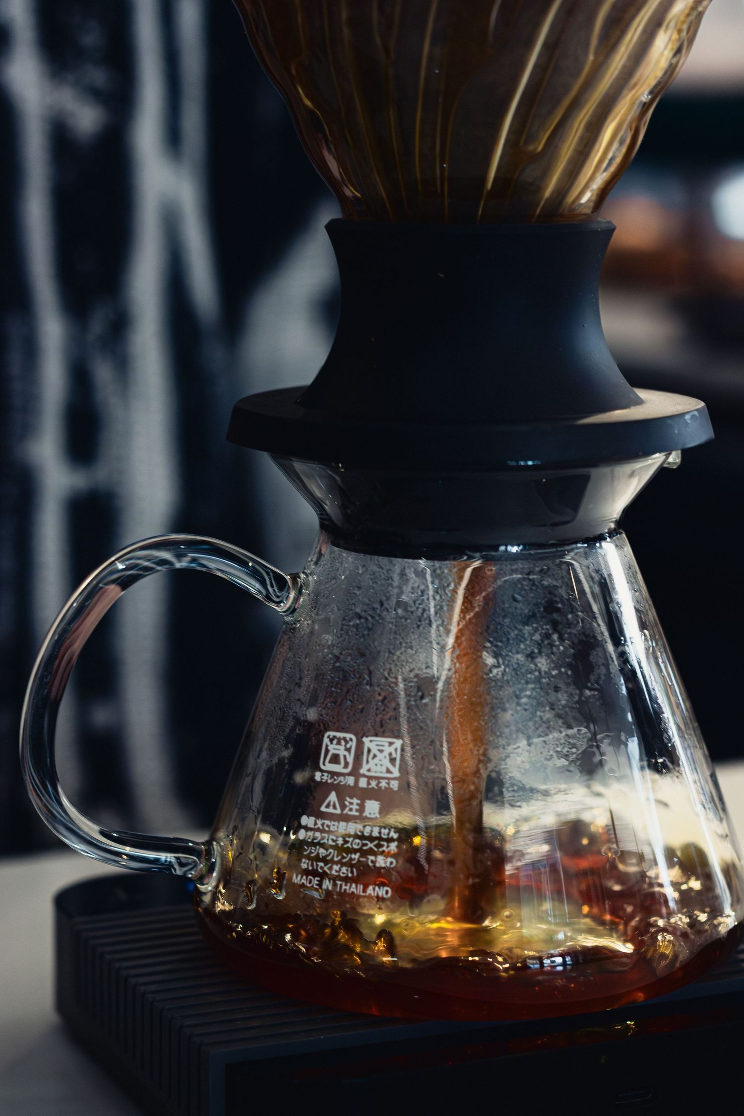 Coffee brewing in a glass pour-over carafe with natural light illuminating the liquid.