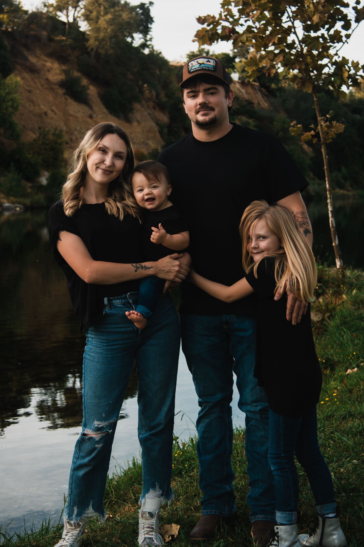 Casual family photoshoot outdoors with everyone wearing matching denim and black outfits.