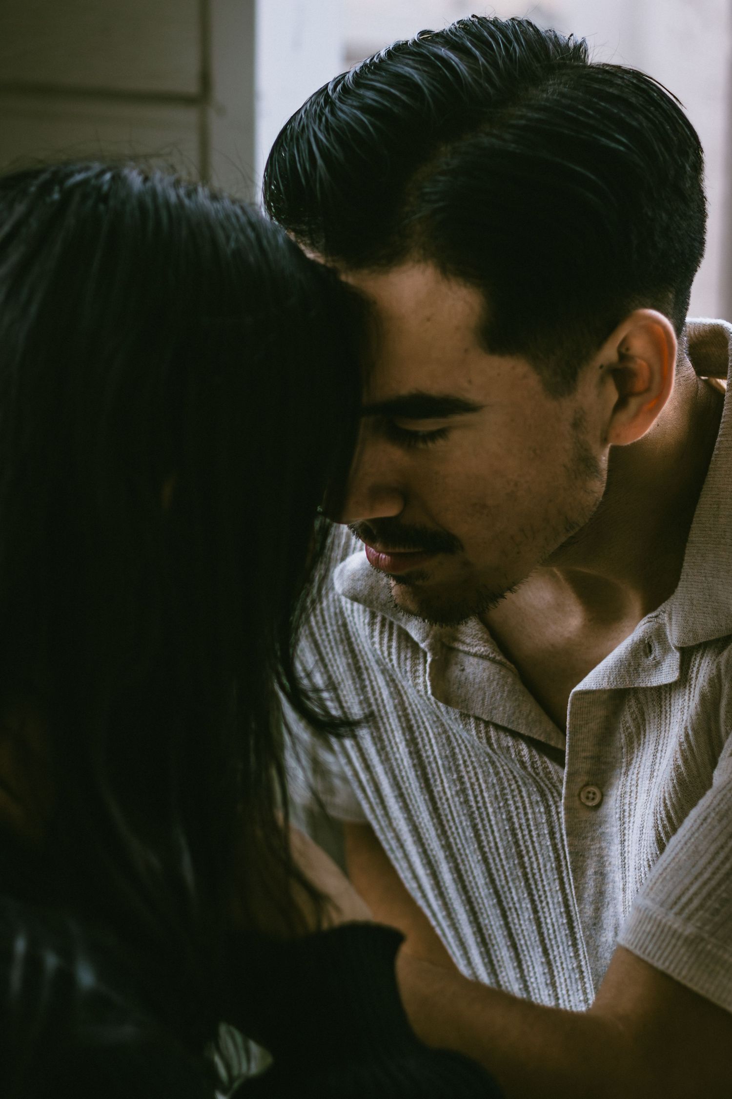 Close-up shot of couple sharing tender moment in moody lighting.