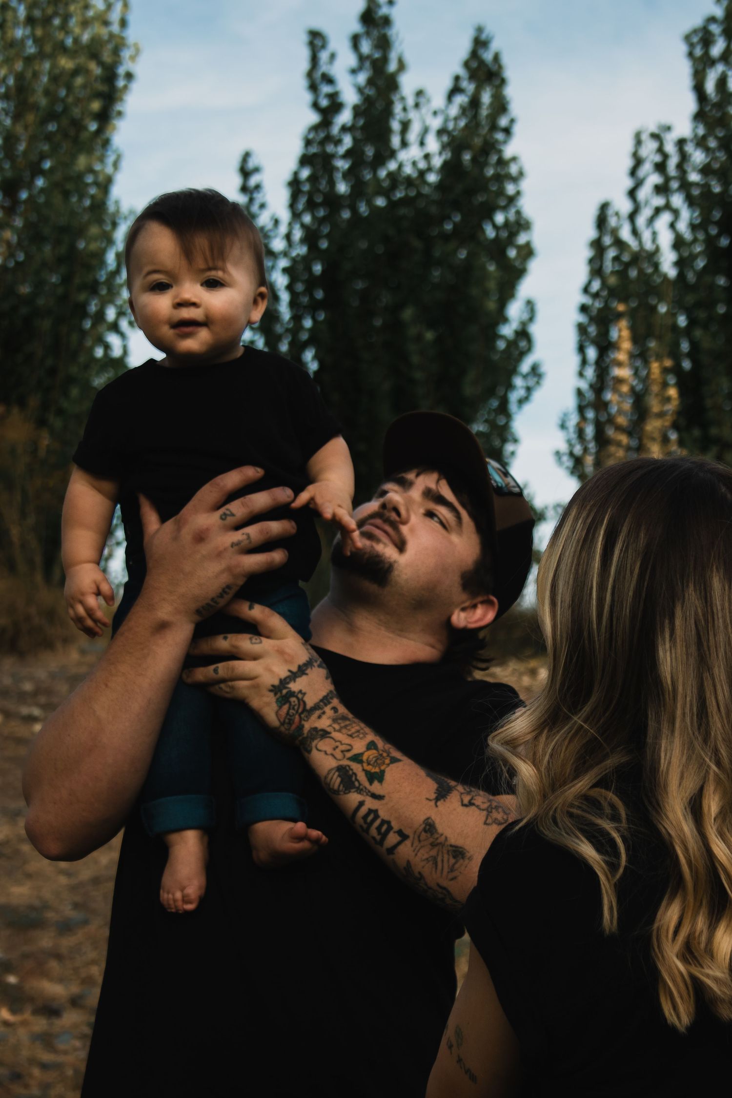 Family sharing joyful moments outdoors against a backdrop of tall trees.