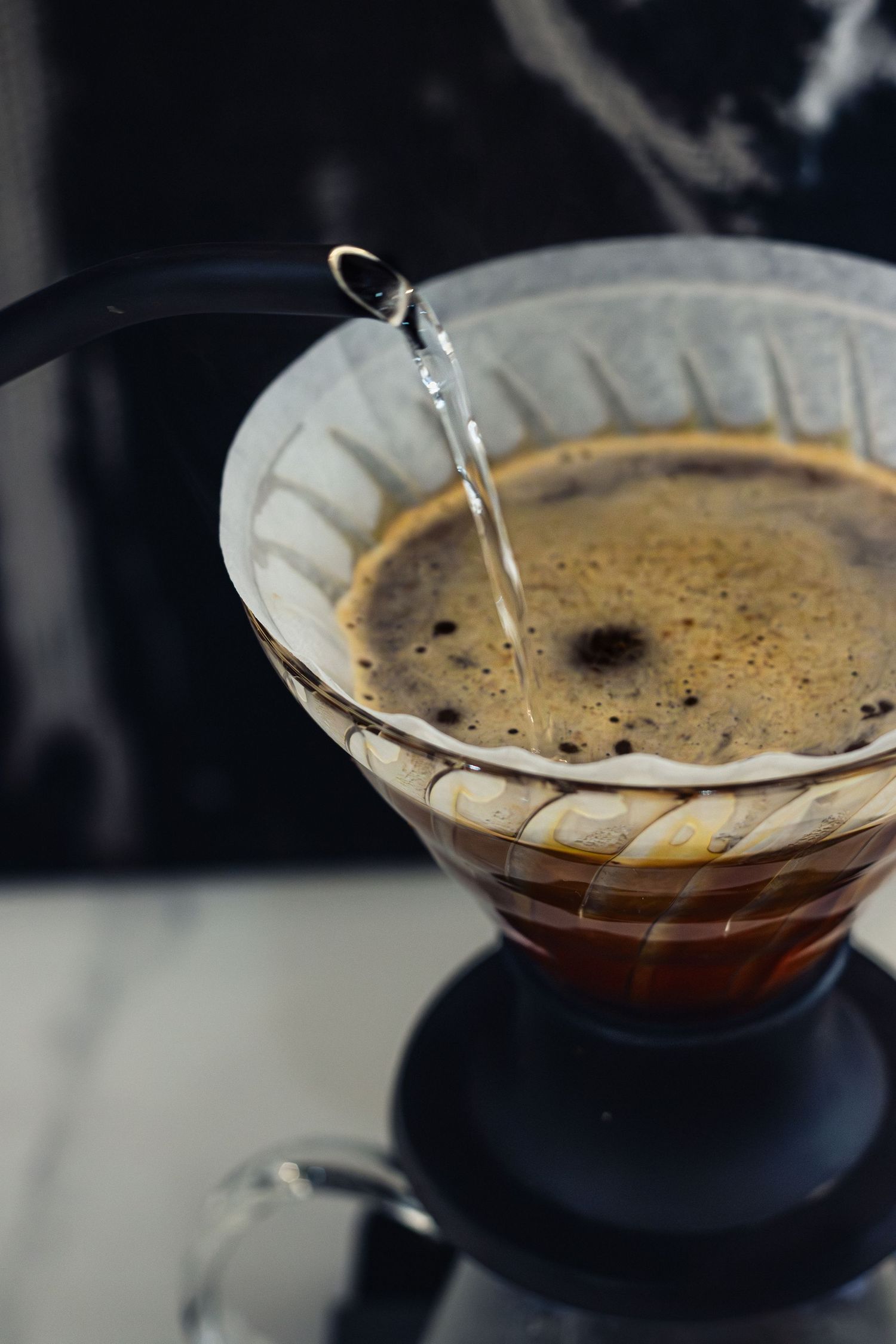 Coffee dripping through paper filter in pour-over setup with morning light.