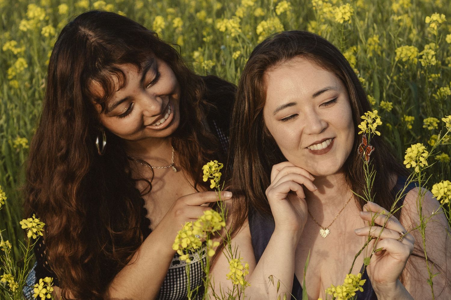 Friends sharing joyful laughter together among bright yellow wildflowers.