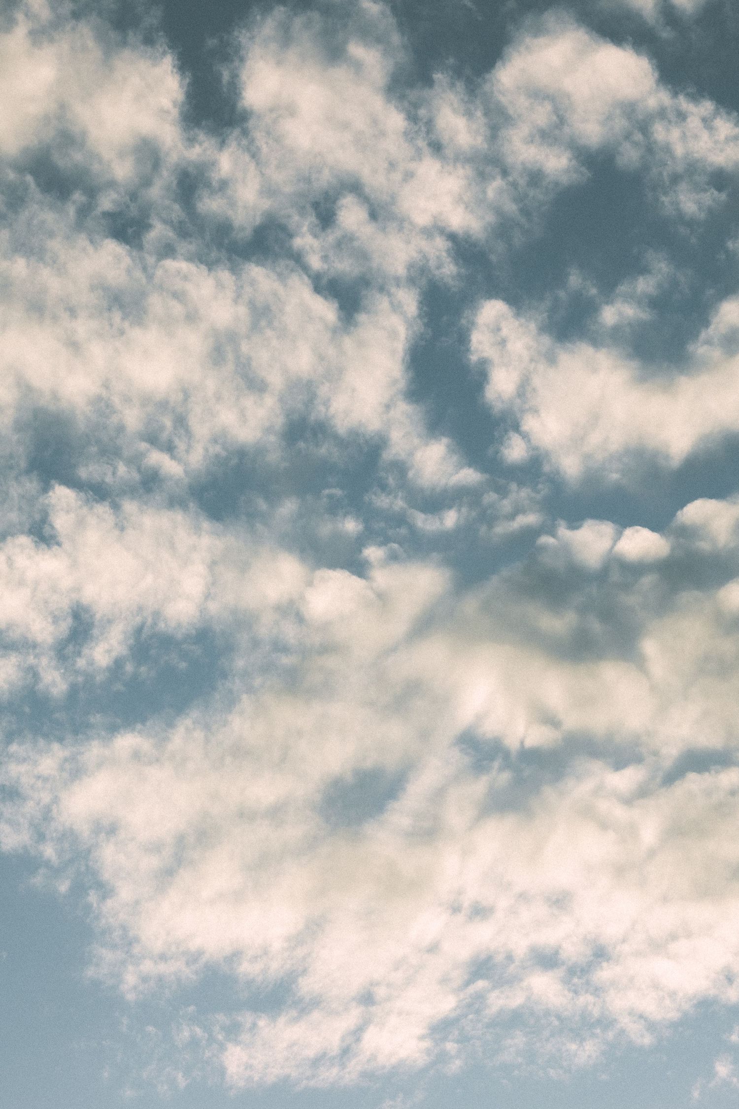 Dramatic cloudy blue sky with scattered white cumulus clouds creating a moody atmospheric backdrop.