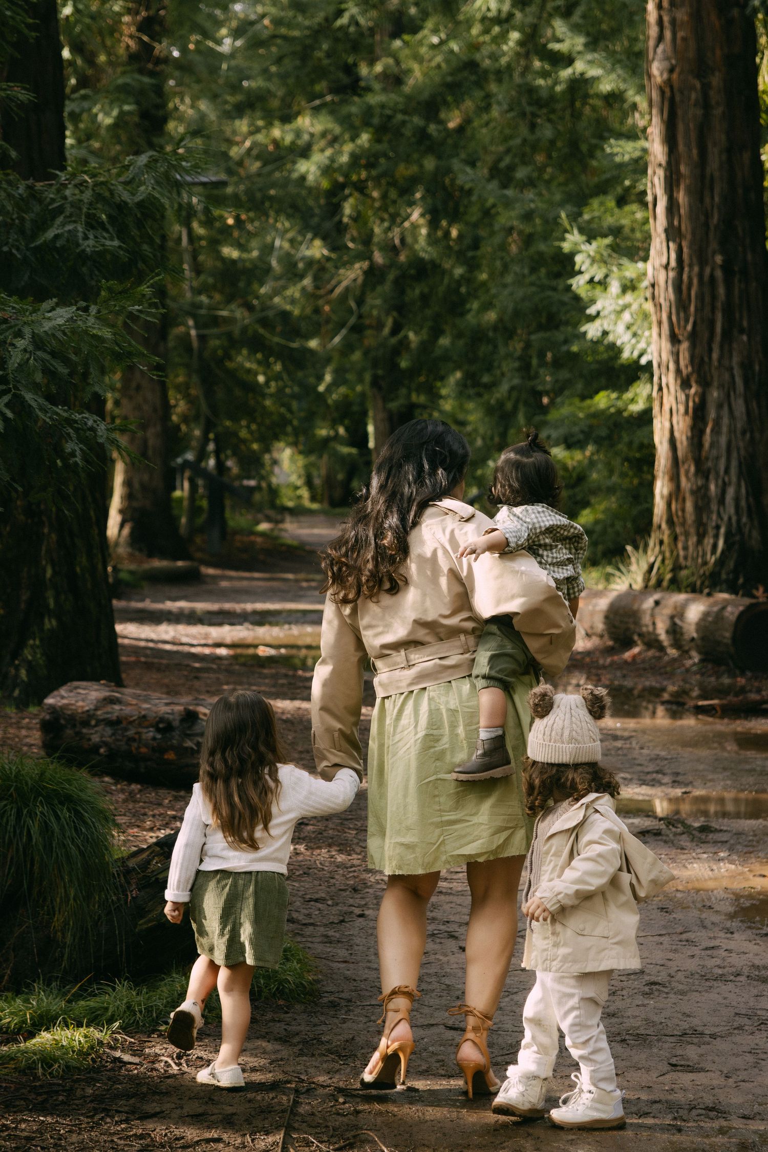 A series of four photos showing people walking on a forest path wearing matching white and olive green outfits.