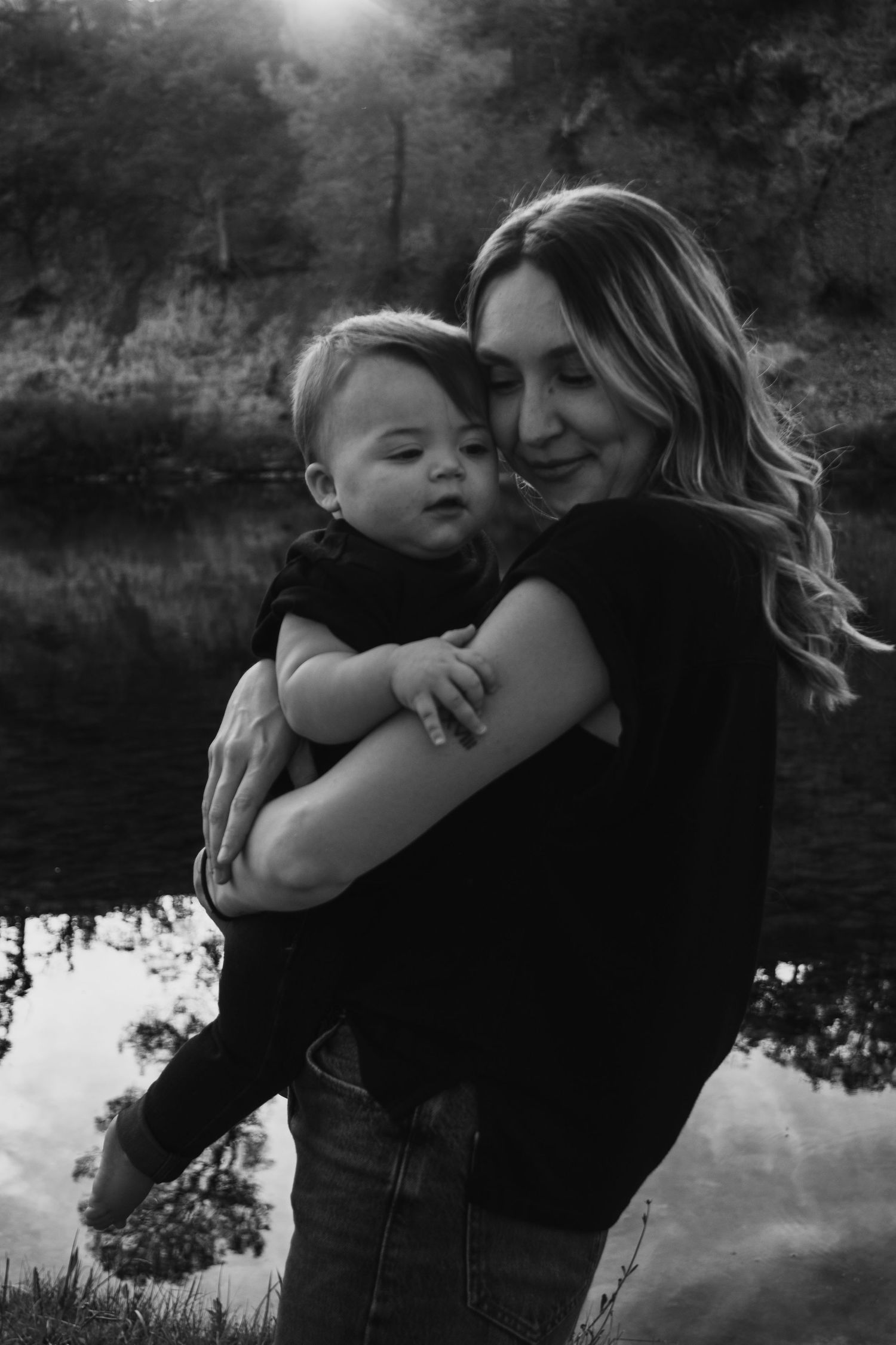 Black and white portraits capturing tender embraces by a reflective lake.