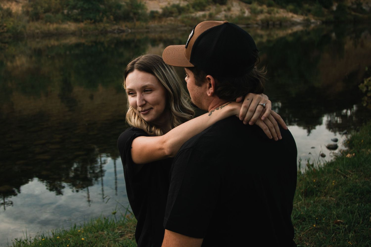 Silhouettes of a couple embracing near a peaceful waterfront at dusk.