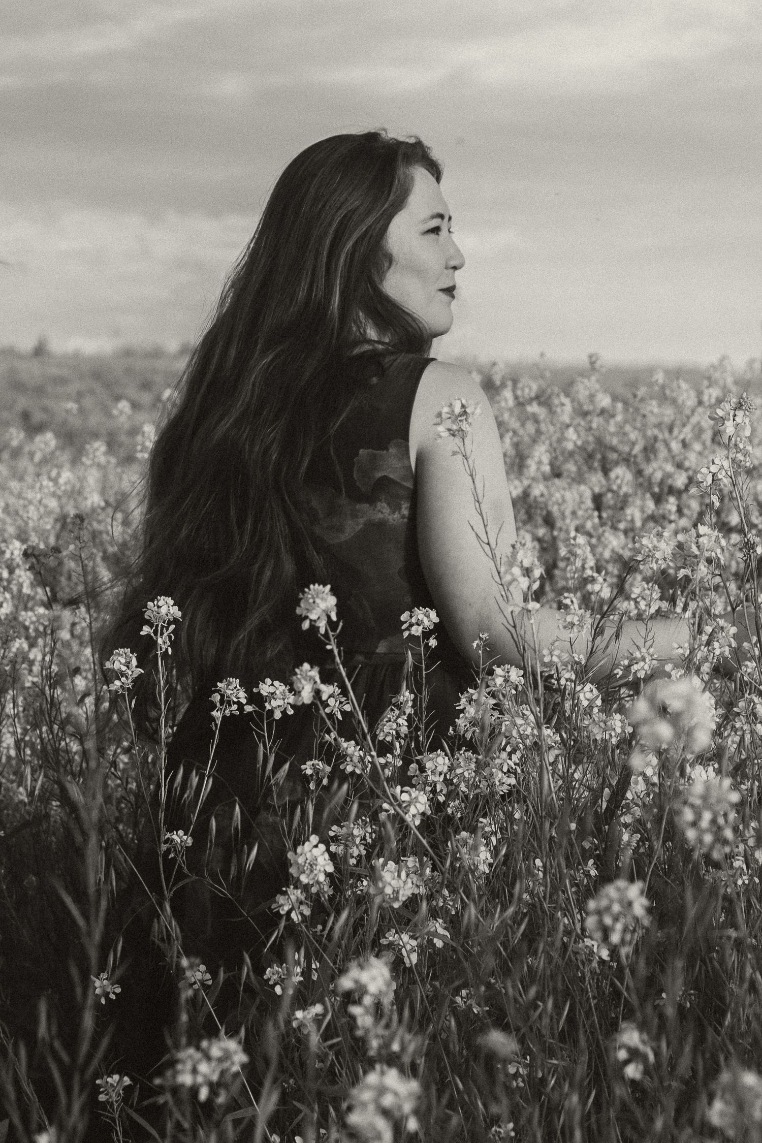 Artistic black and white portrait among blooming white flowers in a meadow.