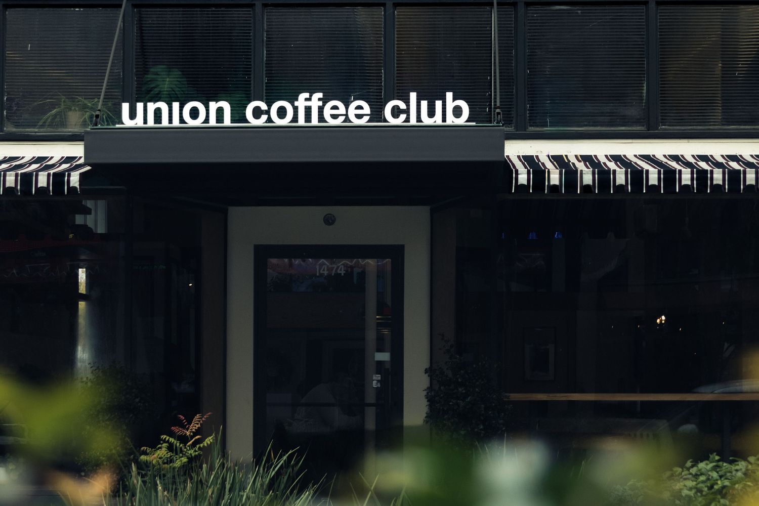 Exterior signage for Union Coffee Club cafe with dark awning and modern storefront design.