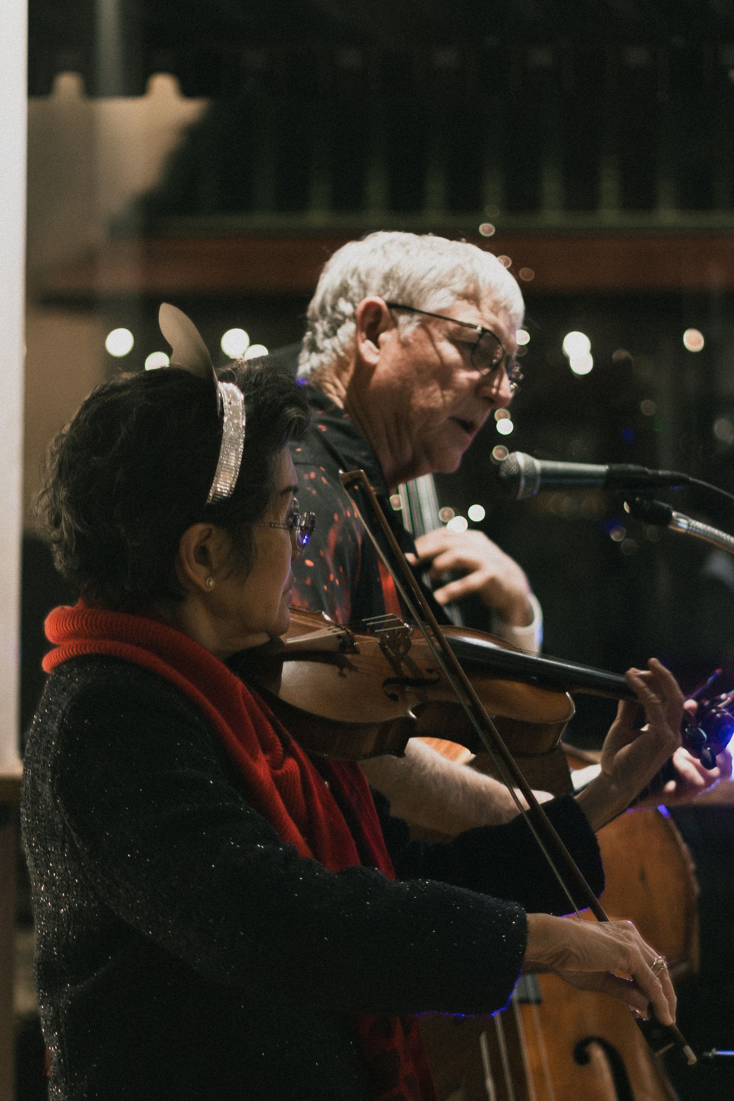 Musicians perform together on stage with violin and microphone during an intimate concert performance.