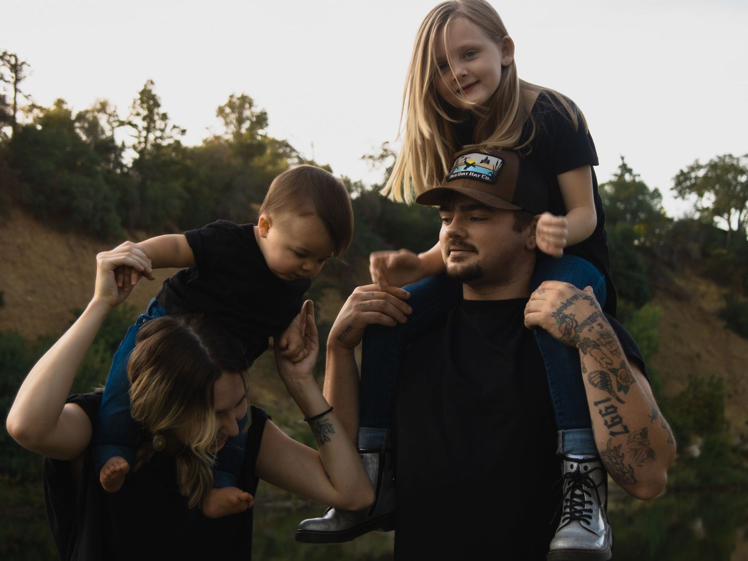 Family enjoying playful moments together by a lake during golden hour.