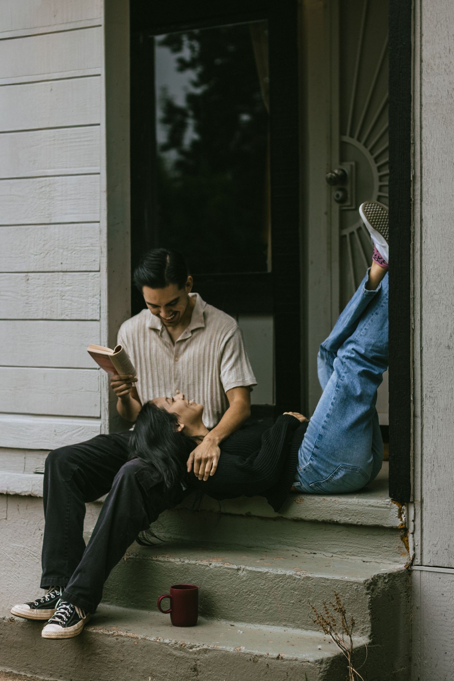 Two people sitting casually on a white porch having a relaxed conversation.