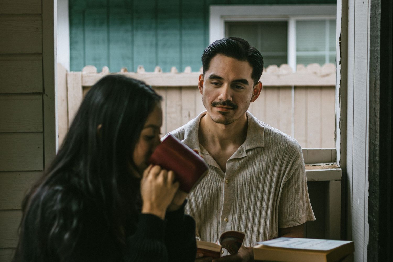 Couple enjoying a conversation on a white porch with natural lighting.