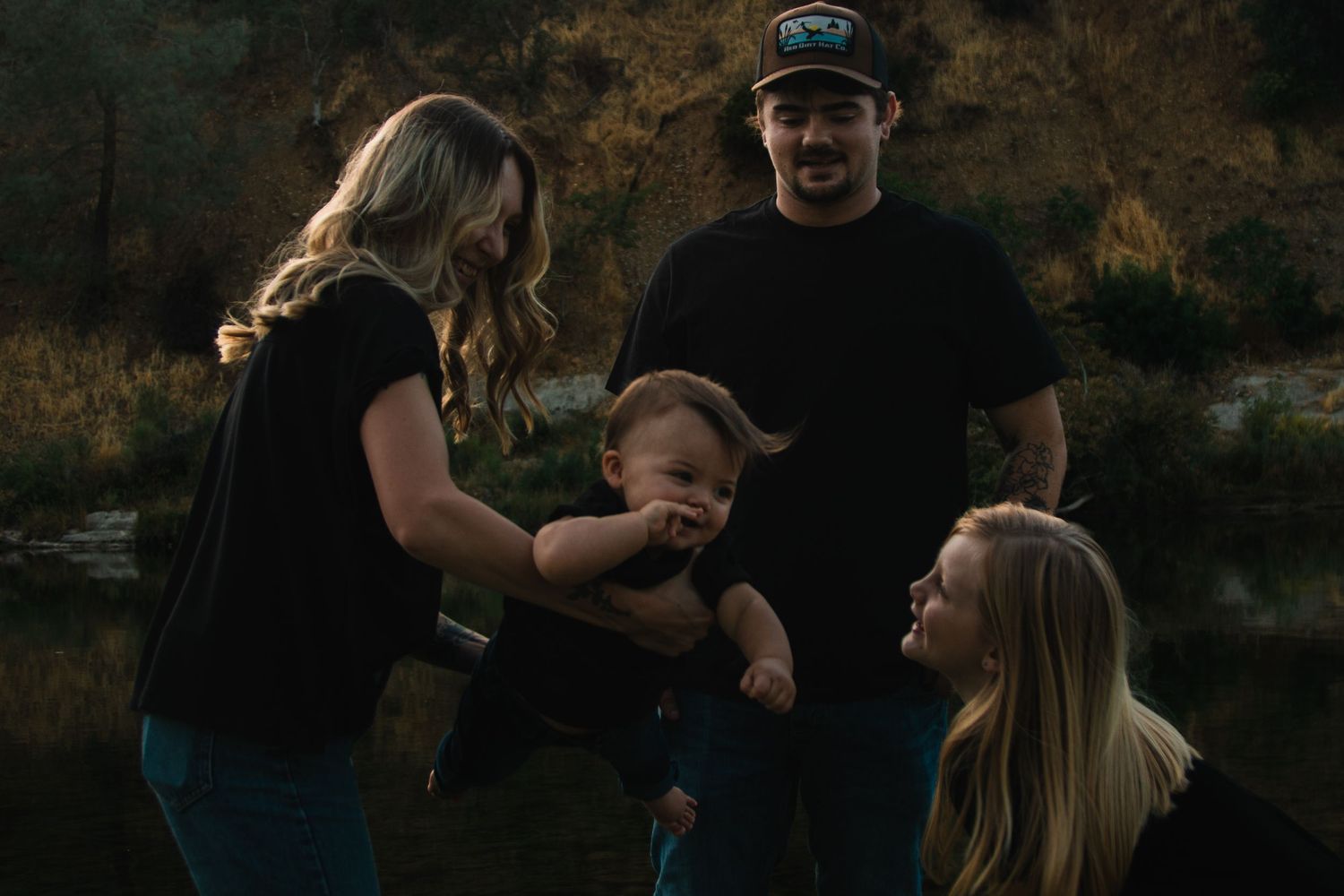 A family shares a playful moment together outdoors during golden hour in a natural setting.
