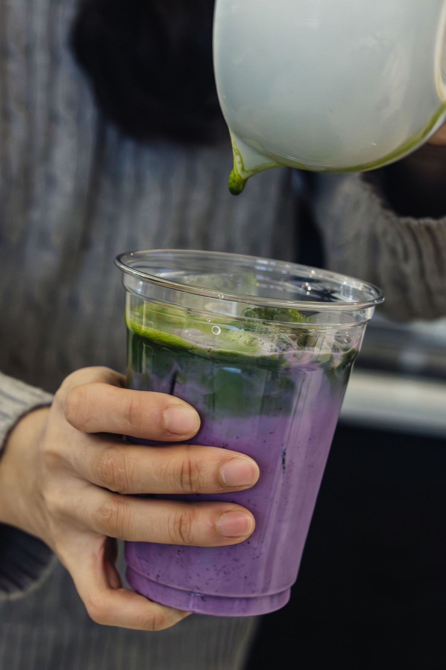 Purple gradient beverage in clear plastic cup with white garnish.