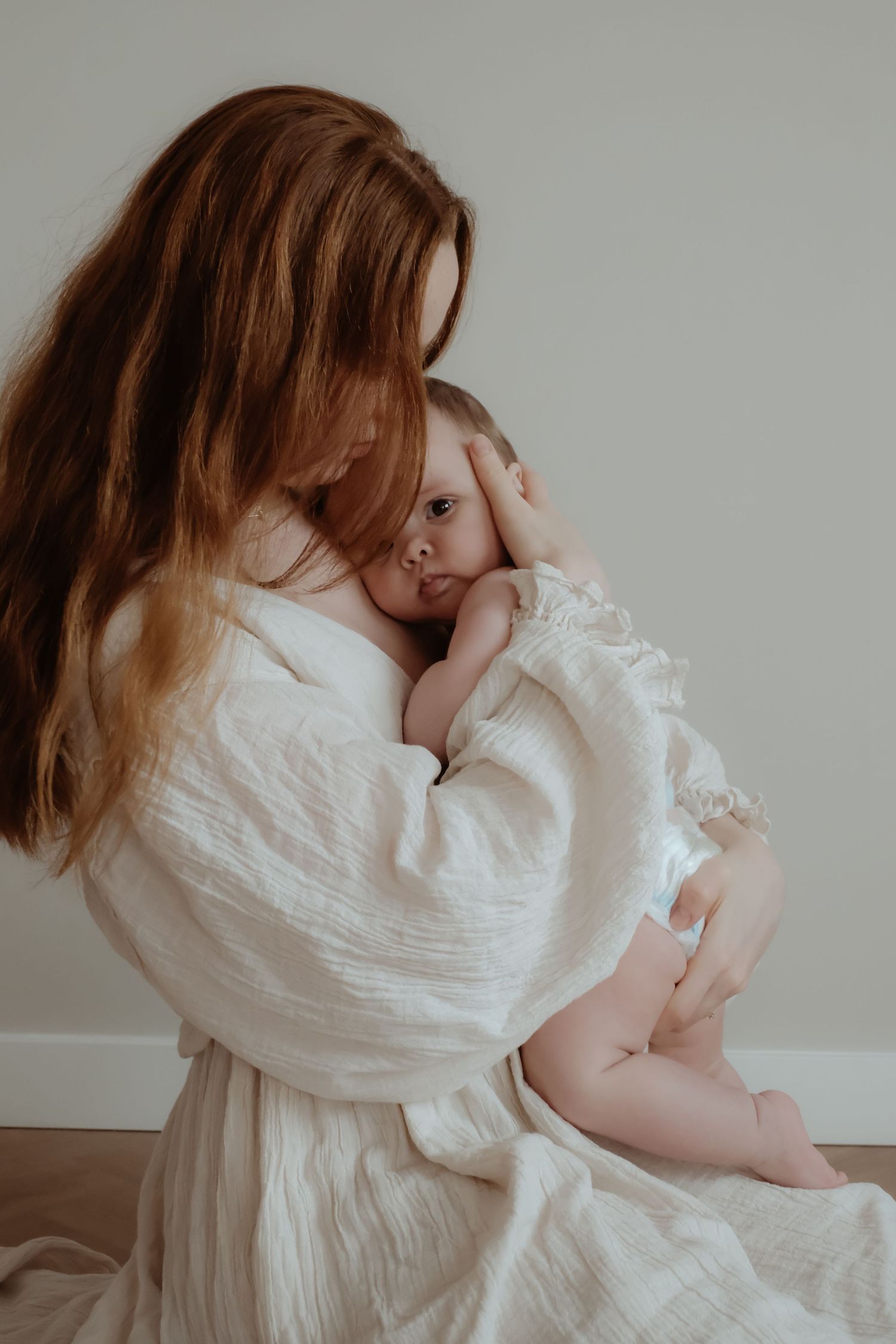 Moeder die haar baby vasthoudt tijdens een intieme motherhood fotoshoot