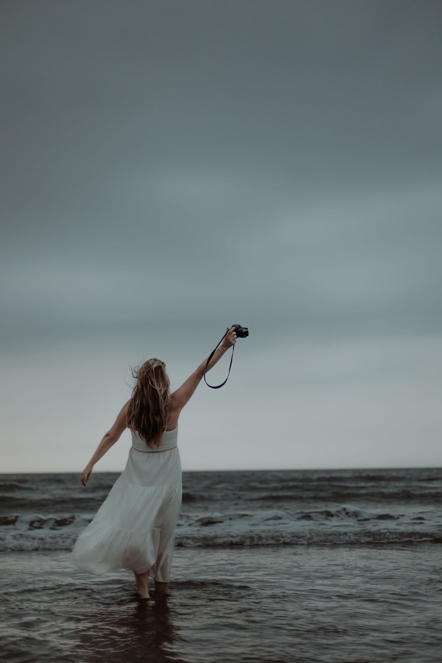 Vrouw in zee met haar armen omhoog tijdens een persoonlijke fotoshoot
