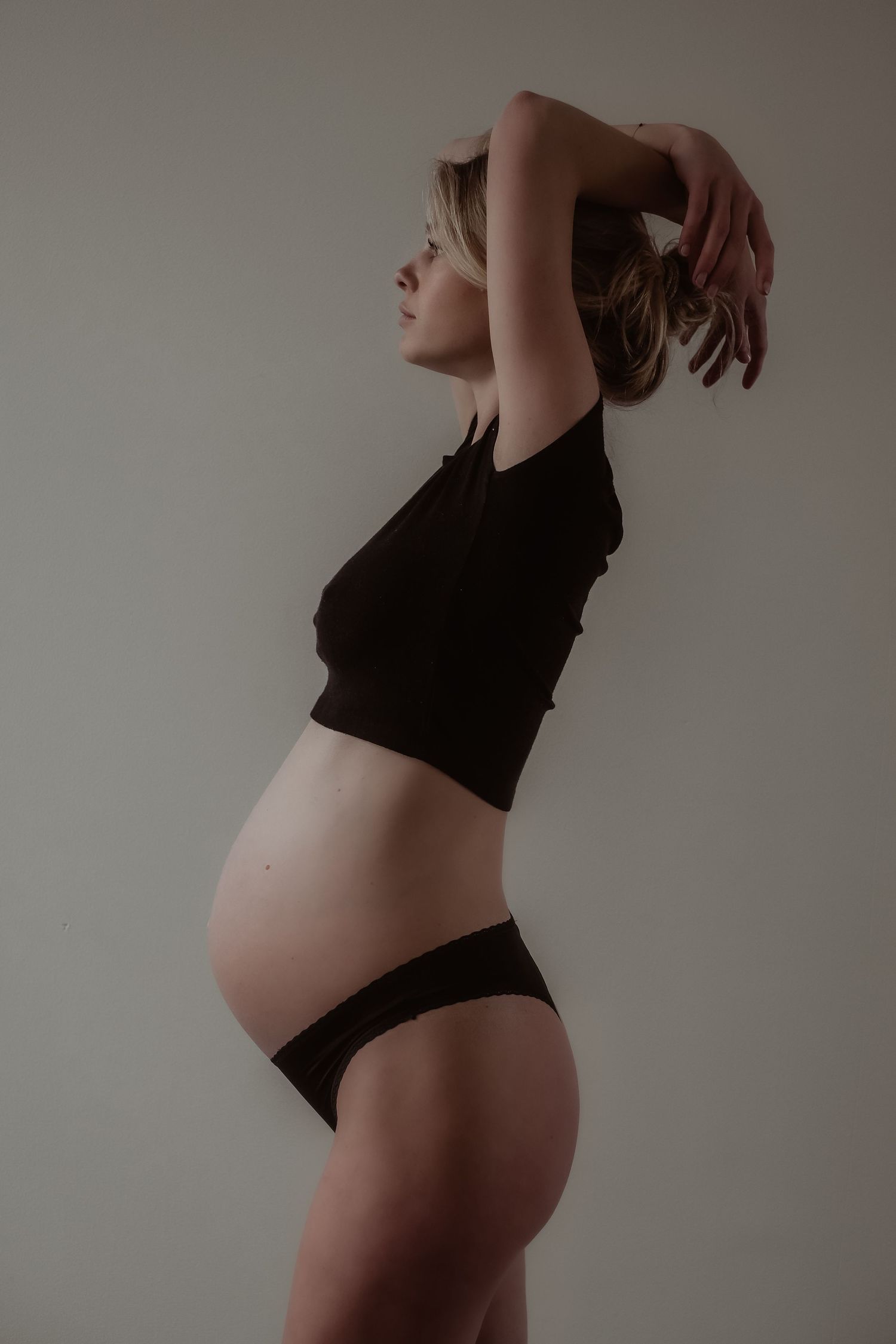 Zwangere vrouw in zijaanzicht tijdens een motherhood fotoshoot