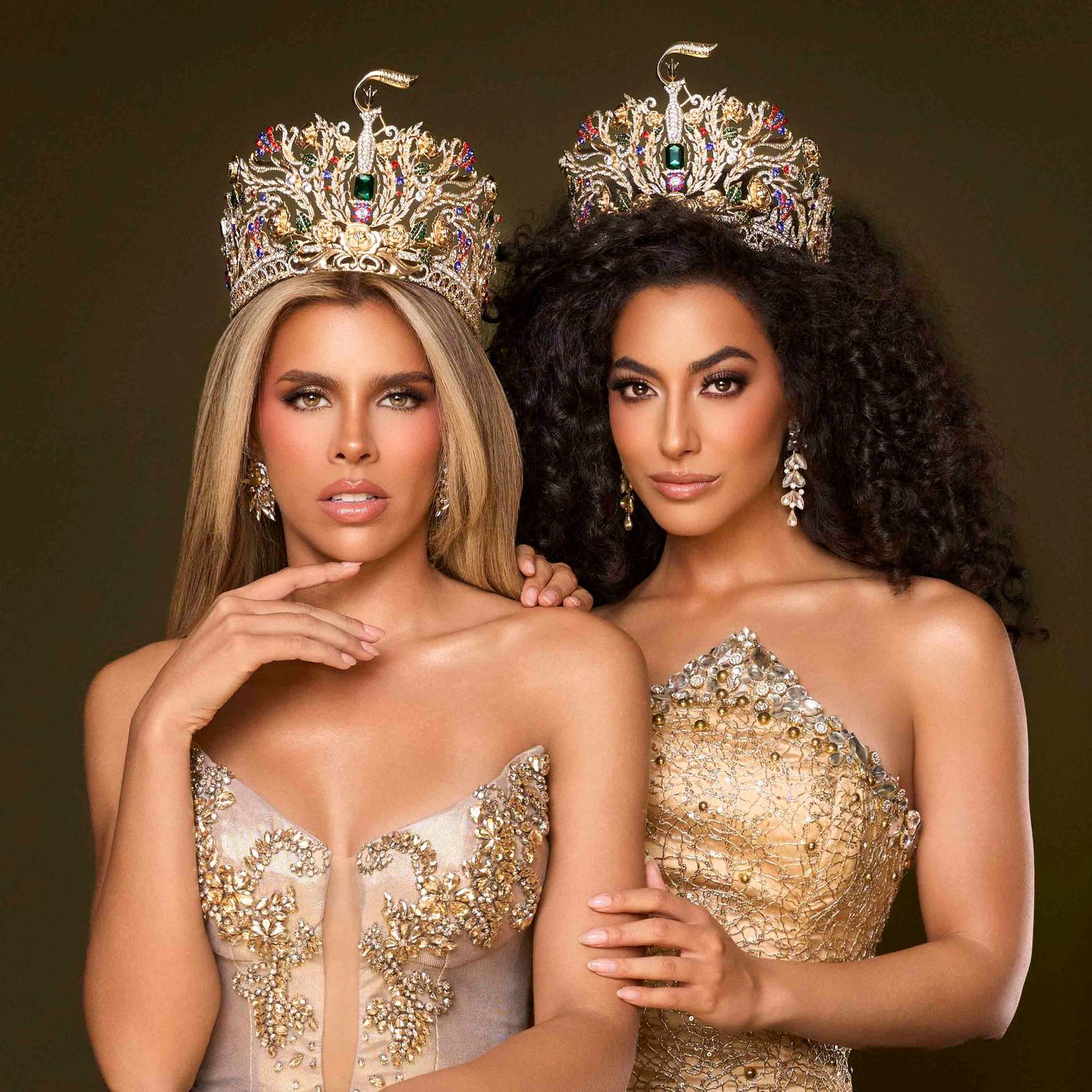 Two beauty queens wearing elaborate gold jeweled crowns and gold gowns posing together for portrait.