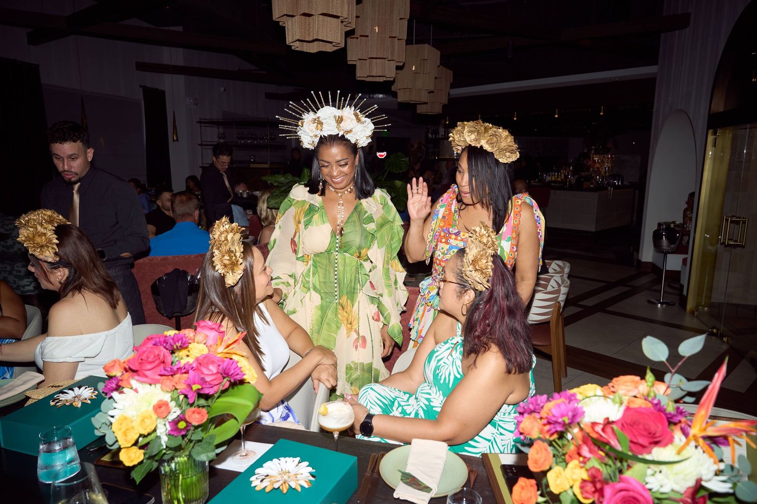 Polynesian dancers in vibrant tropical costumes entertain guests at a colorful floral-decorated dinner event.