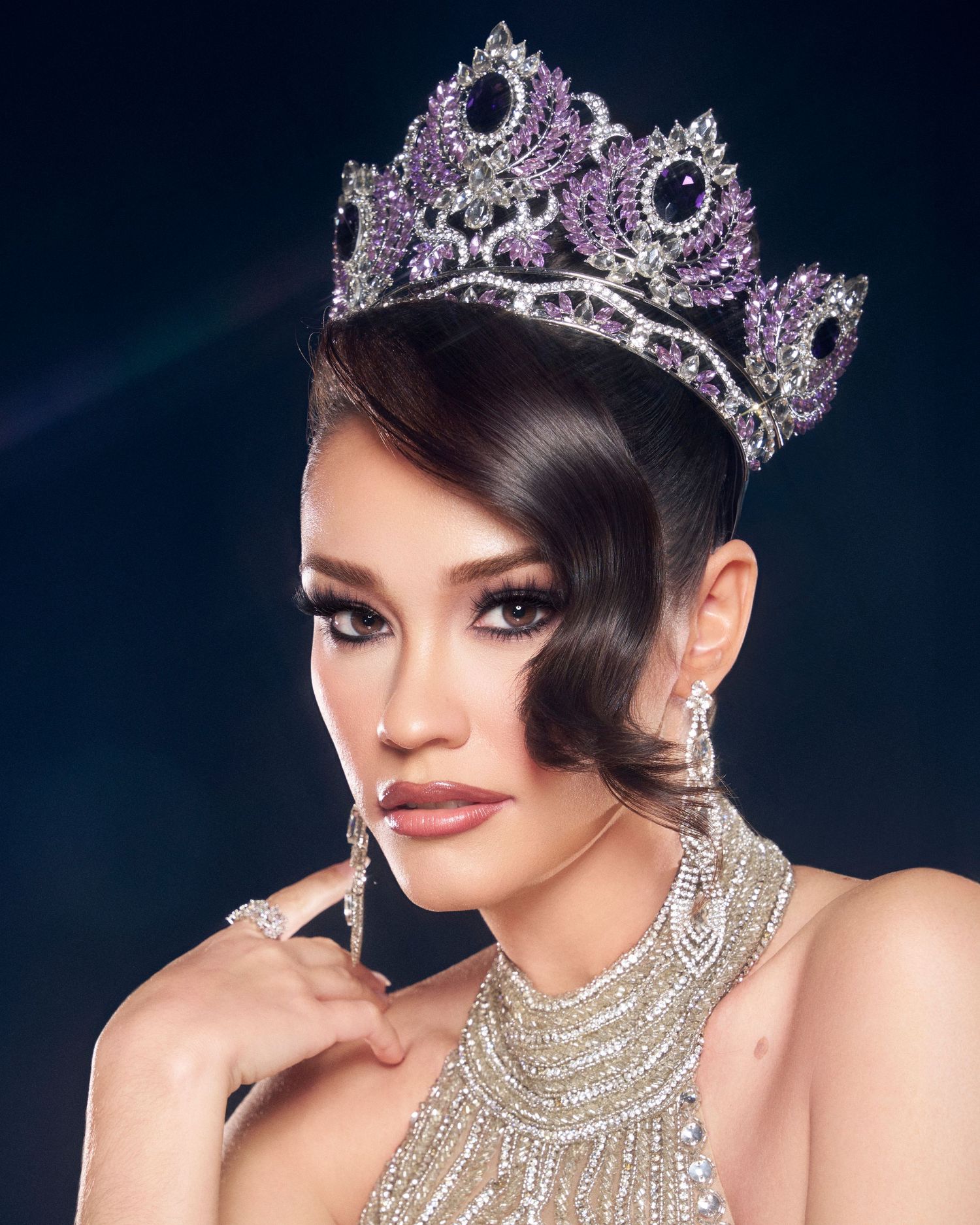Woman wearing large purple and silver pageant crown with matching jewelry.