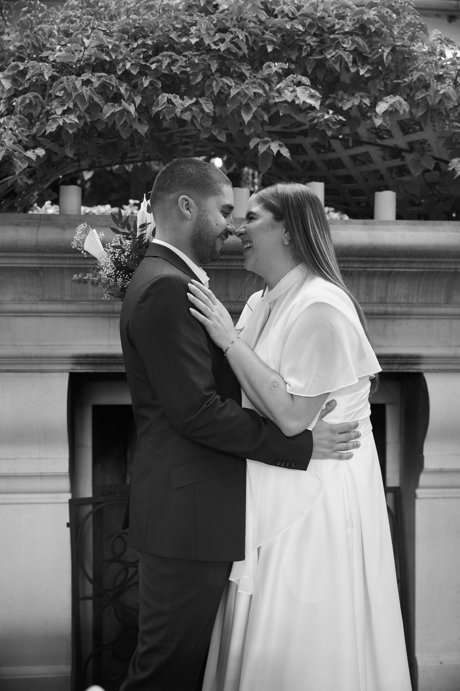 Black and white photo of a bride and groom sharing a romantic moment before their first kiss at an outdoor wedding.