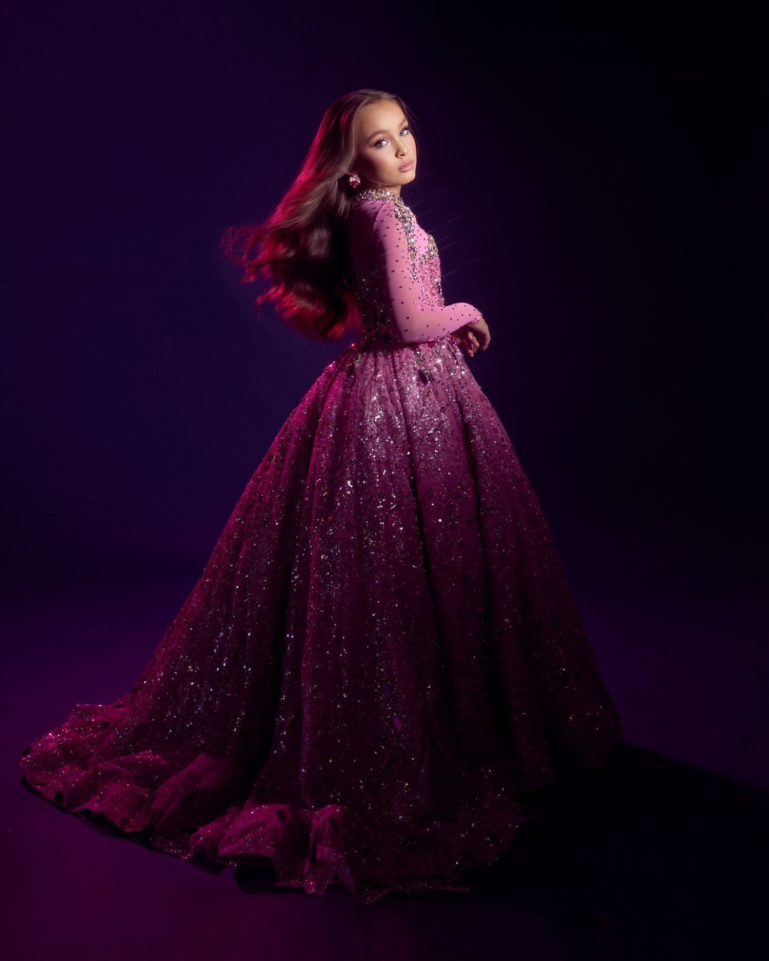 Girl twirls in glamorous magenta sequined ball gown against deep purple background.