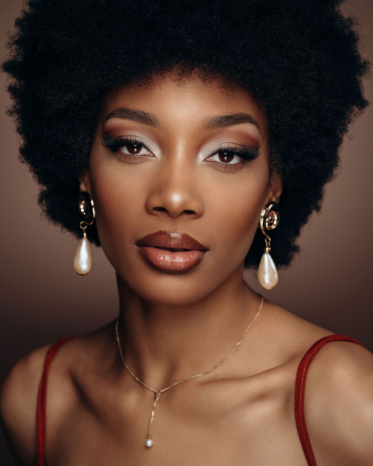 Beauty portrait of a female model with natural afro and elegant styling, captured with soft studio lighting.