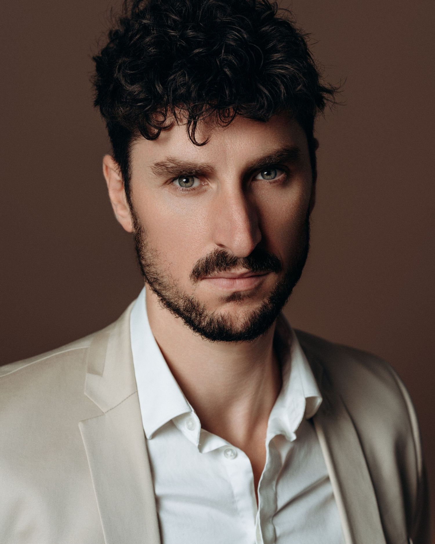 Professional male headshot of a model in a beige blazer with clean studio lighting and a modern editorial look.