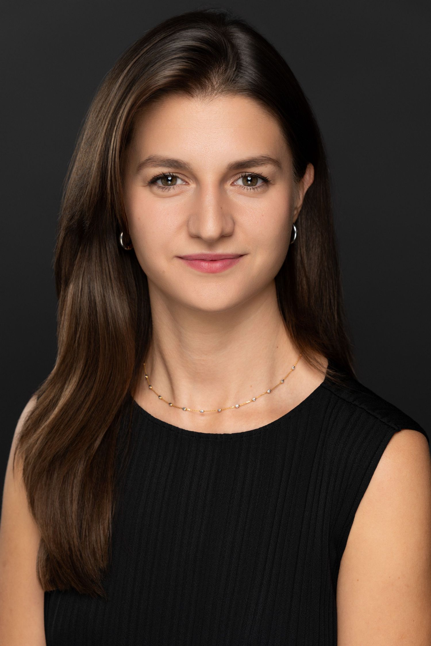 Clean studio headshot of a woman with natural styling and soft lighting on a dark background.