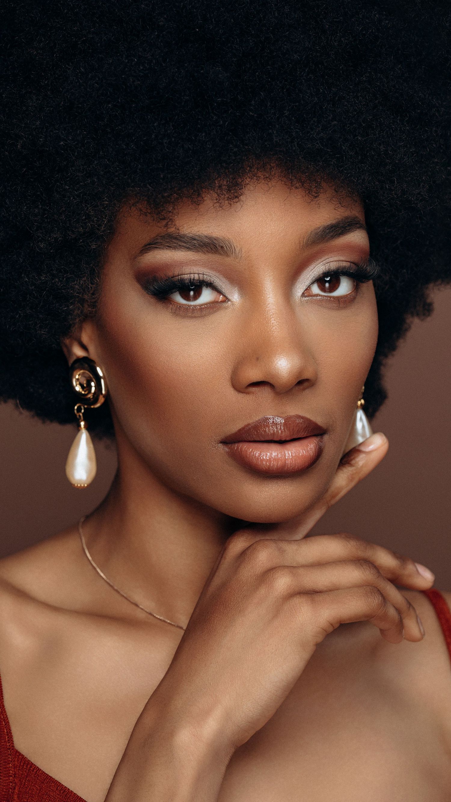 Beauty portrait of a female model with natural afro and elegant styling, captured with soft studio lighting.
