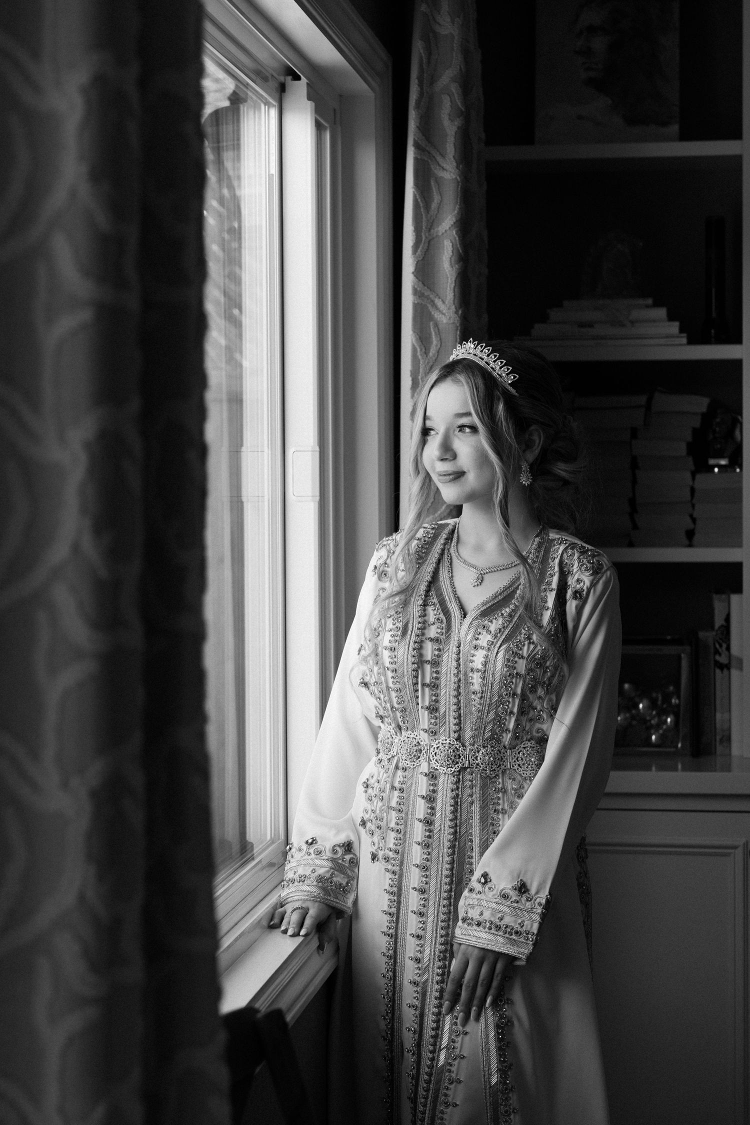 Black and white photograph of a young lady looking through the window