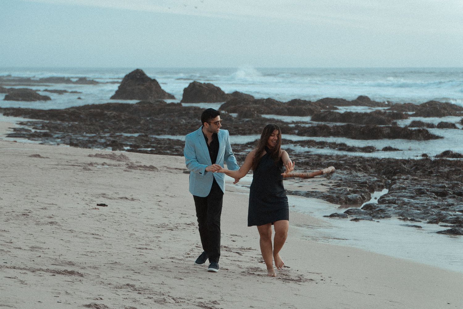 image capturing the moment of an engagement proposal between two people, framed by the timeless beauty of the California coastline
