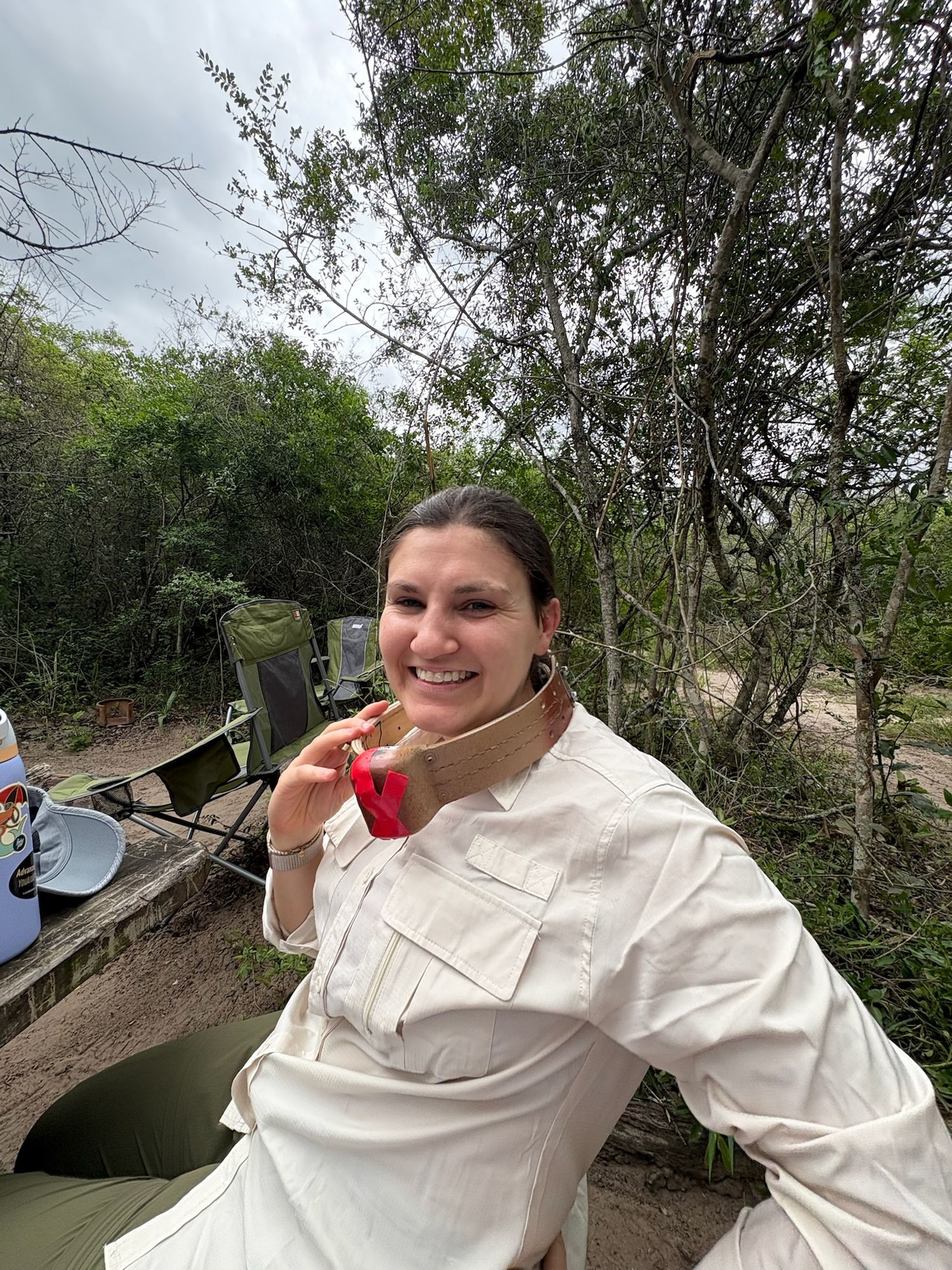 A woman smiling with trees in the background.