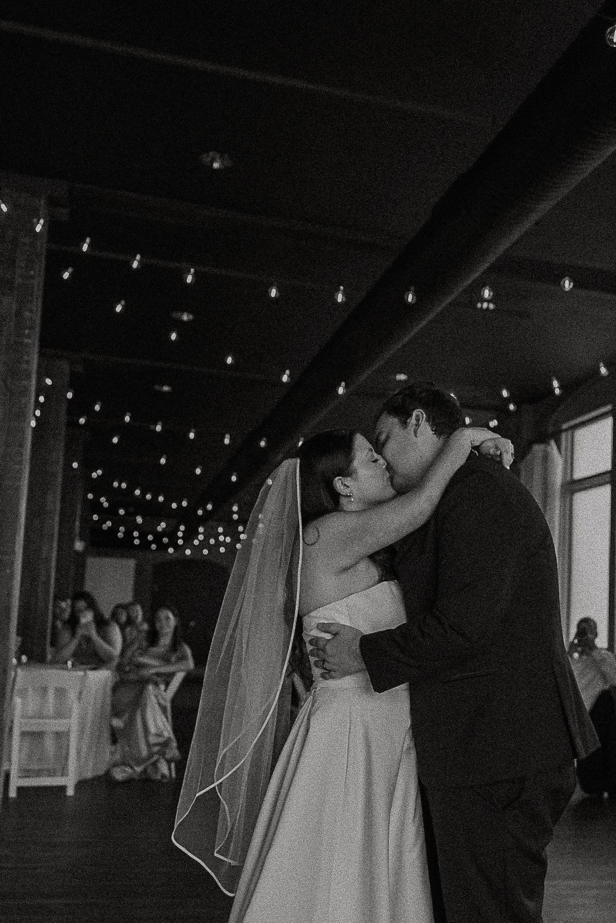 Black and white photo of bride and groom sharing a romantic kiss during their first dance.