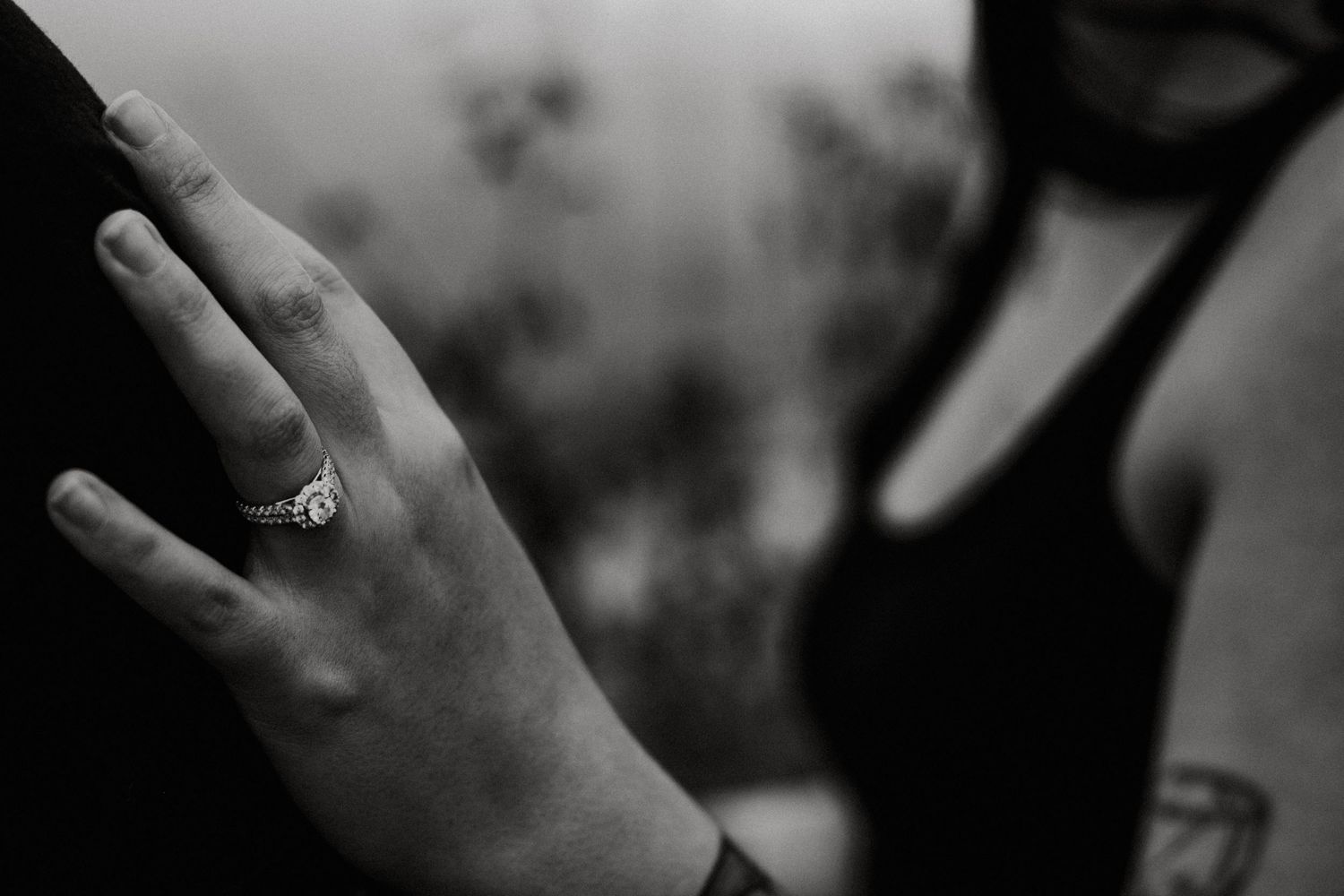 Black and white close-up of womans hand displaying diamond engagement ring against dark background in Dayton, Ohio