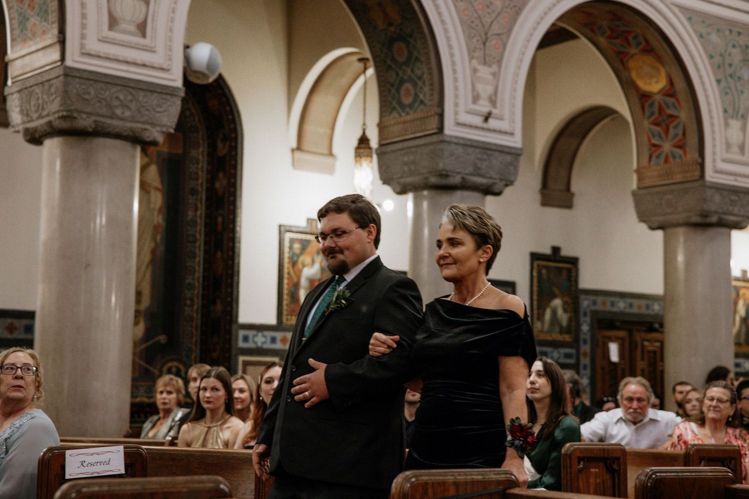 Elegantly dressed couple walking arm in arm down a church aisle during a wedding ceremony in Cincinnati, Ohio