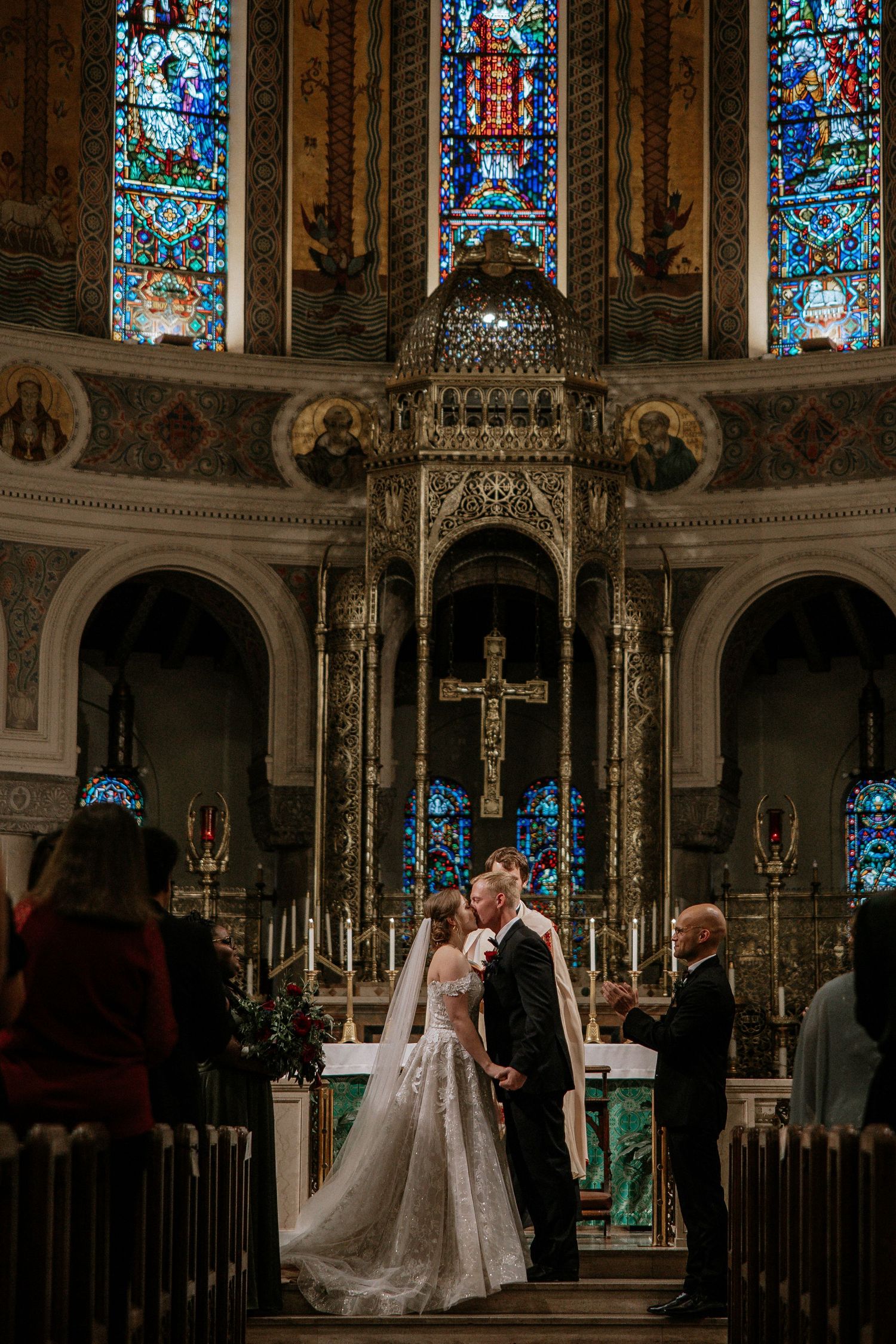 Bride and groom share an intimate moment at ornate church altar surrounded by stained glass windows and candles in Cincinnati, Ohio