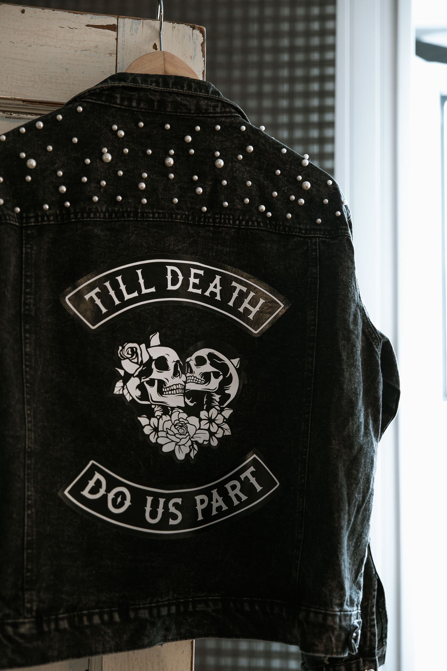 Black studded denim jacket with Till Death Do Us Part skull patch on hanger.